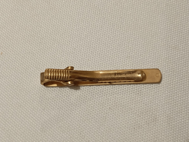 Pince à cravate dorée pincée